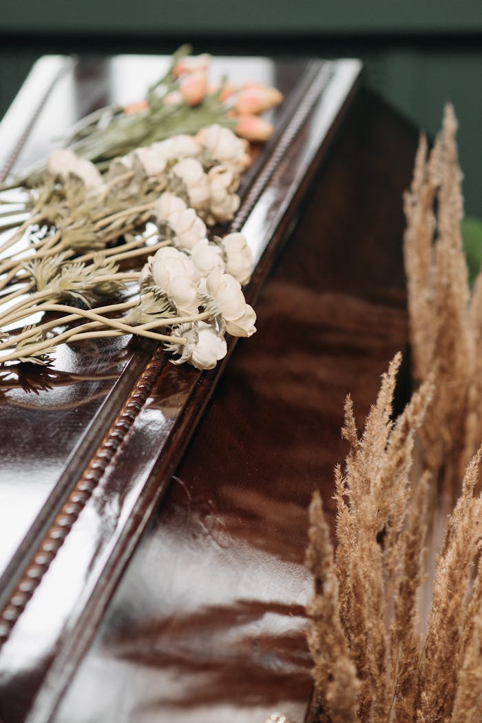 Close-up of a polished coffin adorned with delicate flowers, symbolizing loss and remembrance.
